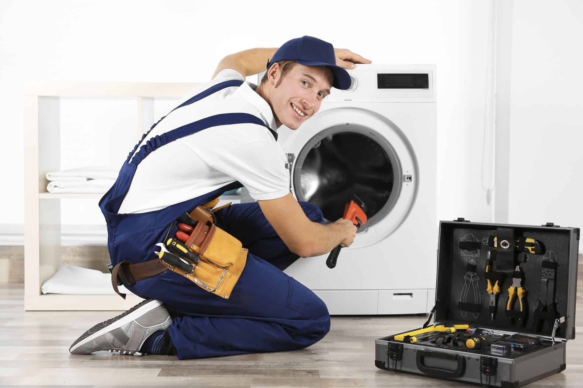 A smiling male mechanic fixing a washing machine